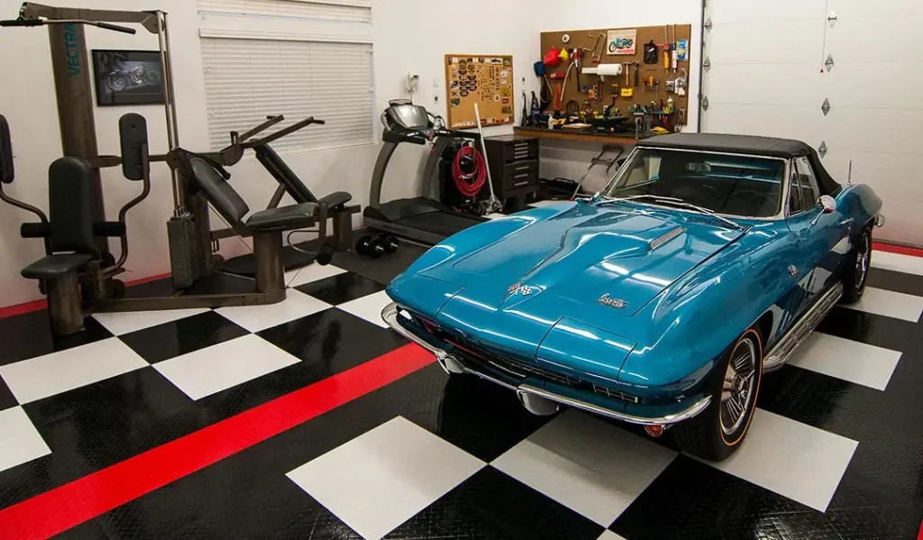 Garage with garage flooring tiles, exercise equipment, and a Corvette