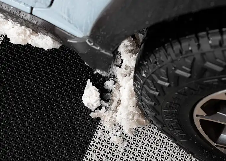 Subaru Crosstrek with all terrain tiers parked on a patio with Deck Tile. The car as tracked snow on to the floor.